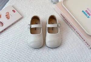 Close-up view of cream-colored children's Mary Jane shoes with strap and soft sole