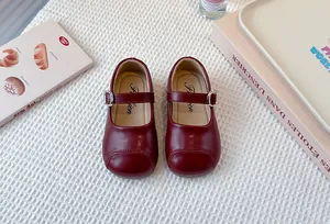 Overhead view of elegant dark red girls' leather Mary Jane shoes with metal buckle detail