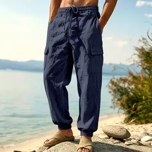 Relaxed fit navy blue linen cargo pants with elastic cuffs for men in outdoor beach setting