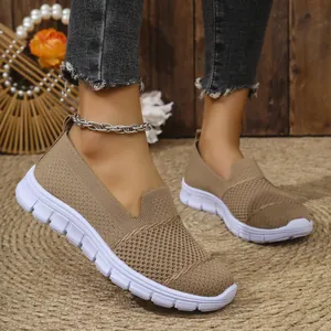 Primer plano de mocasines de malla caqui transpirables para mujer con suelas blancas