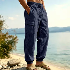 Navy blue linen cargo pants detail with elastic cuffs and side pockets on a beach.
