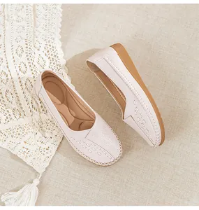 Macro view of comfortable beige leather flat loafers with elegant laser-cut patterns.