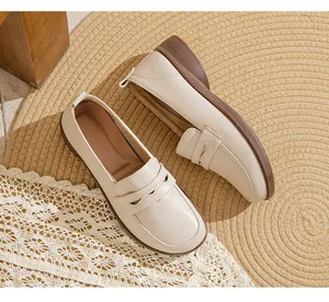 Detailed macro view of cream-colored soft leather penny loafers on a rustic woven rug