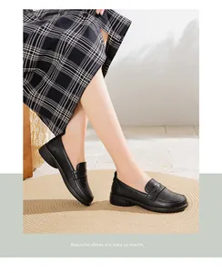 Close-up of comfortable black leather loafers worn with a plaid skirt on a rug