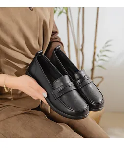 Detailed view of black soft leather loafers held by a person, showing the texture and design.