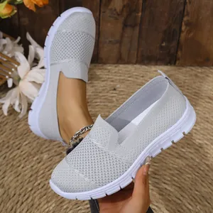 Primer plano de zapatillas grises de malla transpirable para mujer con suelas blancas