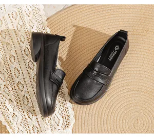 Close-up detail of black soft leather flat loafers for elderly women on straw mat