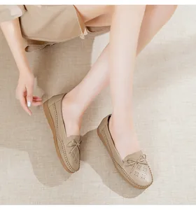 Detail view of comfortable beige flat loafers with bow and laser-cut hollow design.
