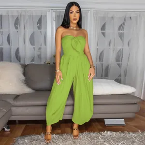 Full length detail of a lime green strapless jumpsuit worn by a model in a lounge area