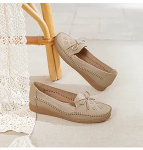 Detailed view of beige breathable loafers with decorative bow and laser-cut patterns