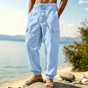Men's light blue linen cargo jogger pants with pockets shown in a beach setting.