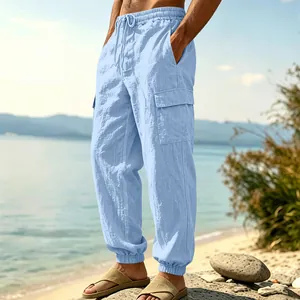 Detail view of light blue linen cargo pants for men styled on a scenic beach background