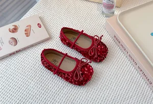 Overhead detail shot of sparkly red sequined girls' Mary Jane shoes on a white surface