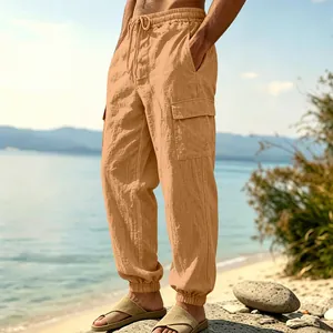 Detailed view of men's loose linen cargo pants featuring side pockets in beach setting