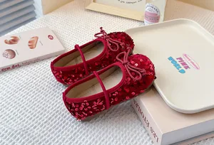 Close-up of shiny red sequined Mary Jane shoes for girls with bow detail and soft sole.