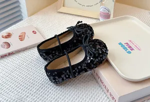 Detailed view of elegant black sequined Mary Jane shoes for girls on a lifestyle setting book