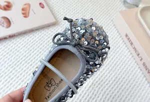 Detailed macro view of a silver sequined girl's princess shoe with a grey bow