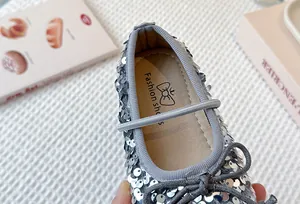 Close-up detail of shimmering silver sequin princess shoes for girls with bow accent