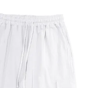 Detailed macro shot of white linen trousers featuring elastic waistband and drawstring cords.