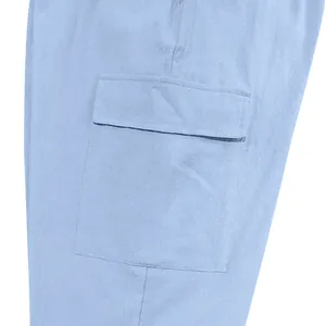 Close-up detail of a large flap cargo pocket on light blue linen men's pants.