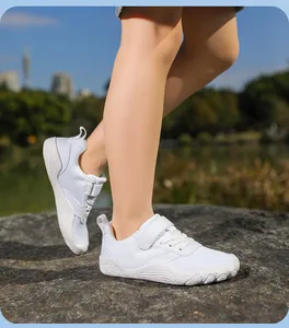 Child wearing white breathable barefoot sneakers on a rock in outdoor natural light