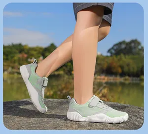 Outdoor view of breathable children's barefoot shoes with flexible soles and green mesh.