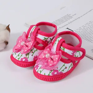 Detailed view of baby girl floral sandals featuring a pink bow and pearl decoration