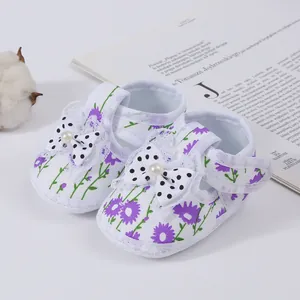 Detailed macro view of baby girl walking shoes with purple floral print and polka dot bow