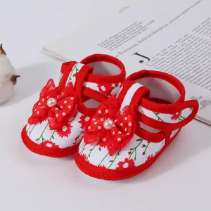 Detail shot of red floral baby girl sandals featuring a cute bow and pearl accent.