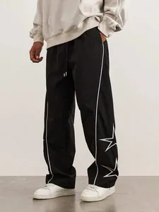 Detailed side view of men's black street track pants with white star embroidery details