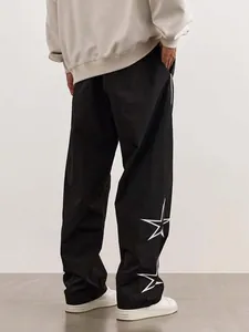 Detail view showing the back of black street-style joggers with white star embroidery.