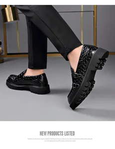 Zwarte loafers met krokodillenprint en dikke plateauzool aan de voeten, zijaanzicht