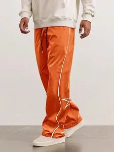Detail view of orange men's high street joggers with white piping and star embroidery