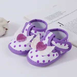 Close-up of purple polka dot baby girl sandals with glitter heart and white wing decor