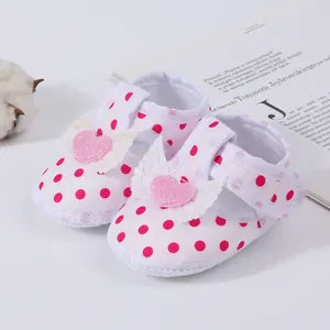 Detailed view of pink heart and angel wing decorations on white polka dot baby girl sandals