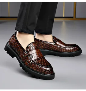 Detailweergave van bruine herenloafers met krokodillenreliëf, dubbele gespen en dikke zool.