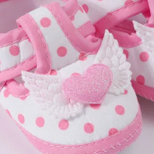 Detail view of pink polka dot baby girl sandals with glittery heart and wing decor