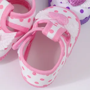 Detailed macro shot of baby girl sandals featuring pink polka dots and sparkly heart wings