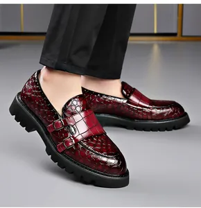Detail van bordeauxrode loafers met krokodillenpatroon, dubbele gespen en grove profielzool.
