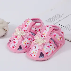 Close-up detail of pink floral baby sandals with butterfly applique for infant girls