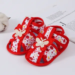 Detailed shot of red floral baby sandals with decorative butterfly accents and soft sole.