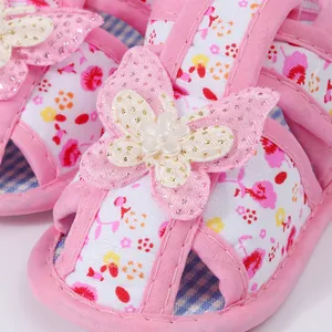 Detailed macro view of 3D butterfly and pearl ornament on pink floral baby girl sandals