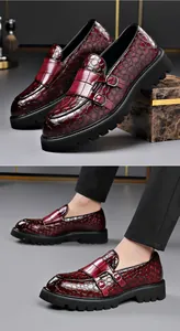 Close-up van bordeauxrode loafers van reliëfleer met dubbele gespen en dikke zolen.