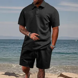 Men's black jacquard polo and shorts set shown in detail against a sunny beach background