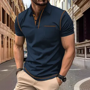 Détail d'un polo bleu foncé pour homme avec des coutures orange contrastées et poche.
