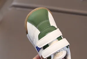 Close-up detail of white and green PU leather baby walking shoes with Velcro straps