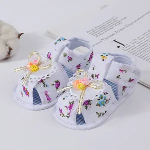 Close-up detail of white baby girl floral sandals with lace and 3D flower decoration