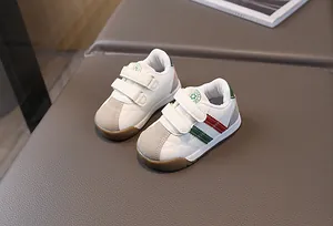 Close-up detail of white toddler sport sneakers featuring grey accents and iconic stripes.