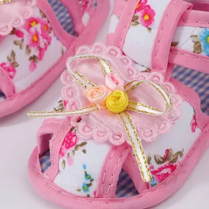 Detailed macro view of pink floral baby sandal featuring lace heart and ribbon rose accents