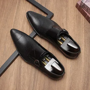 Vue de dessus de chaussures monk strap en cuir noir perforé avec embauchoirs en bois